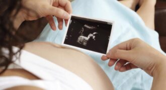 Bebé recién nacido y calendario que muestra los meses con más nacimientos